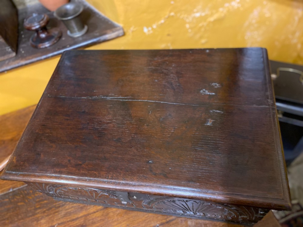 A dark oak wooden bible box featuring a flat hinged top, an iron lock plate, and hand-carved demi-lune fan motifs across the front panel. View VI