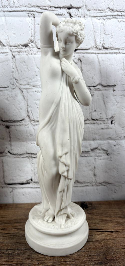 A pair of 19th-century unglazed white Parian ware porcelain figures depicting classical maidens in draped garments, standing on circular integrally moulded plinths. View III