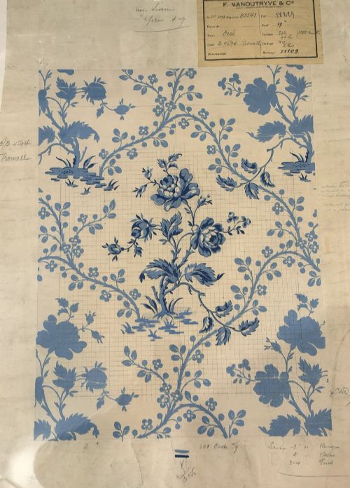 fig 1. A framed vintage French textile design featuring a blue floral motif rendered on grid paper, complete with technical handwritten annotations and an original manufacturer label.