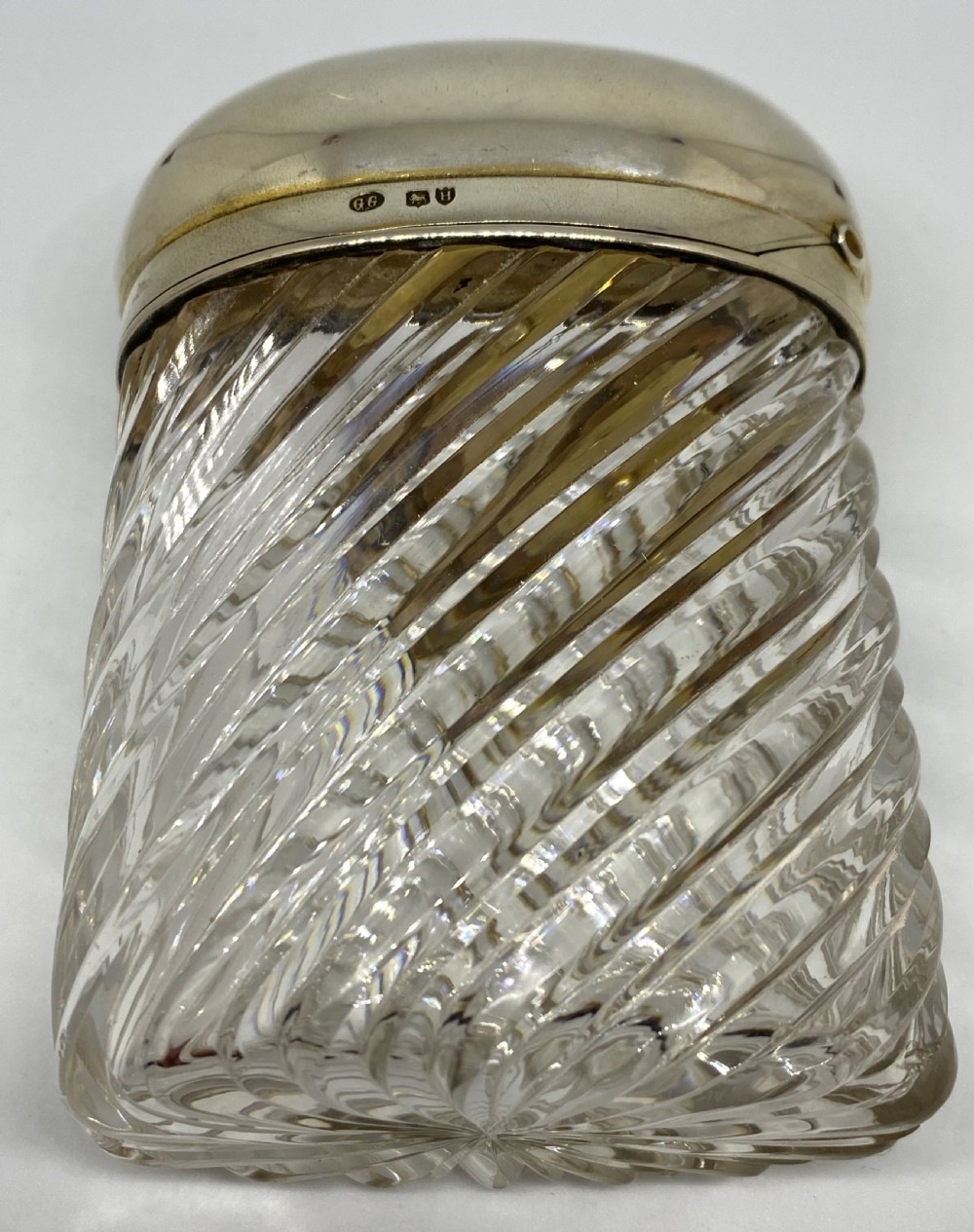 A spiral-cut clear glass cologne bottle featuring a hinged silver lid with a gilt interior and internal locking tab. View II