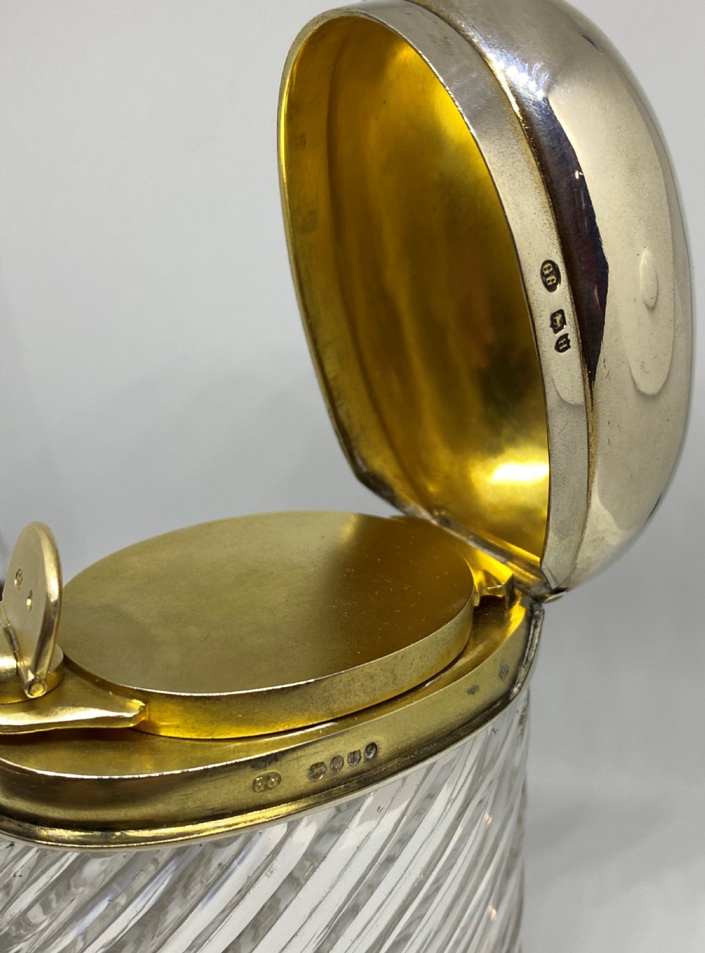 A spiral-cut clear glass cologne bottle featuring a hinged silver lid with a gilt interior and internal locking tab. View IV