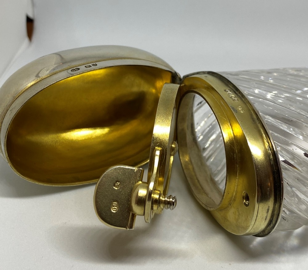 A spiral-cut clear glass cologne bottle featuring a hinged silver lid with a gilt interior and internal locking tab. View VII