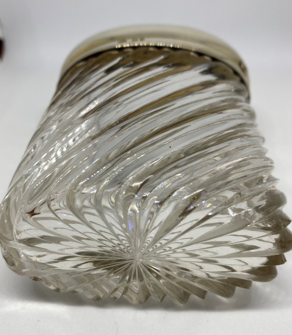 A spiral-cut clear glass cologne bottle featuring a hinged silver lid with a gilt interior and internal locking tab. View IX