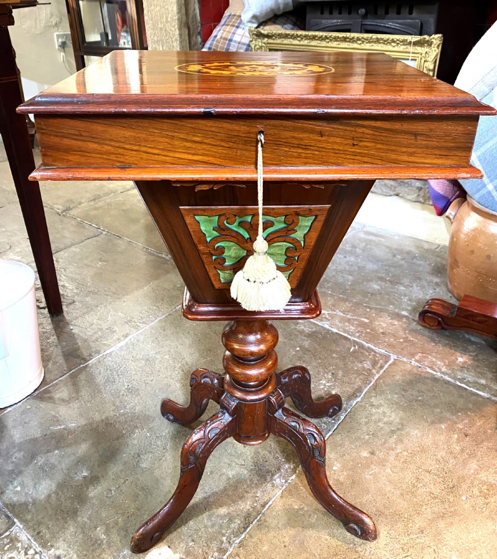 A Victorian walnut sewing table featuring a hinged lid decorated with an oval floral marquetry inlay set upon a carved tripod pedestal base. View II