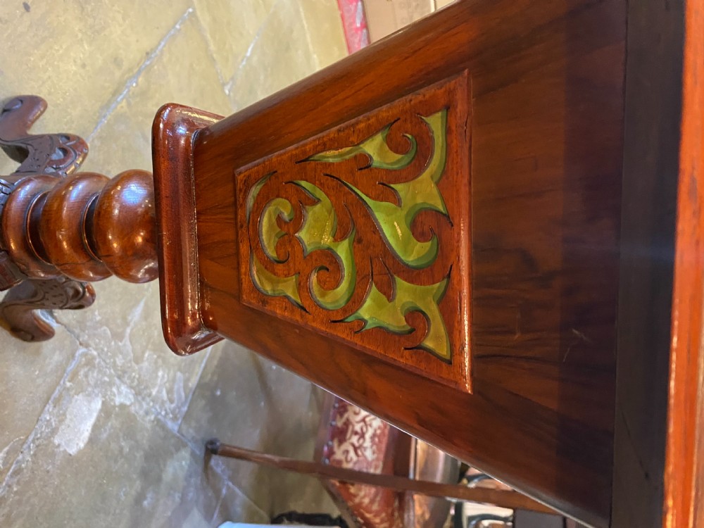 A Victorian walnut sewing table featuring a hinged lid decorated with an oval floral marquetry inlay set upon a carved tripod pedestal base. View X