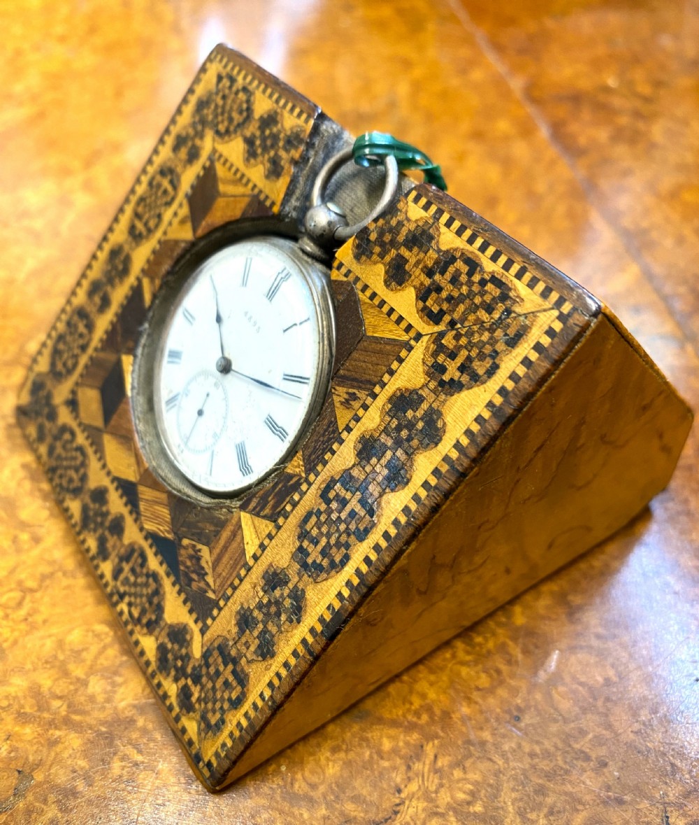 A square Victorian Tunbridge ware wooden pocket watch stand featuring geometric mosaic parquetry around a central pocket watch. View II