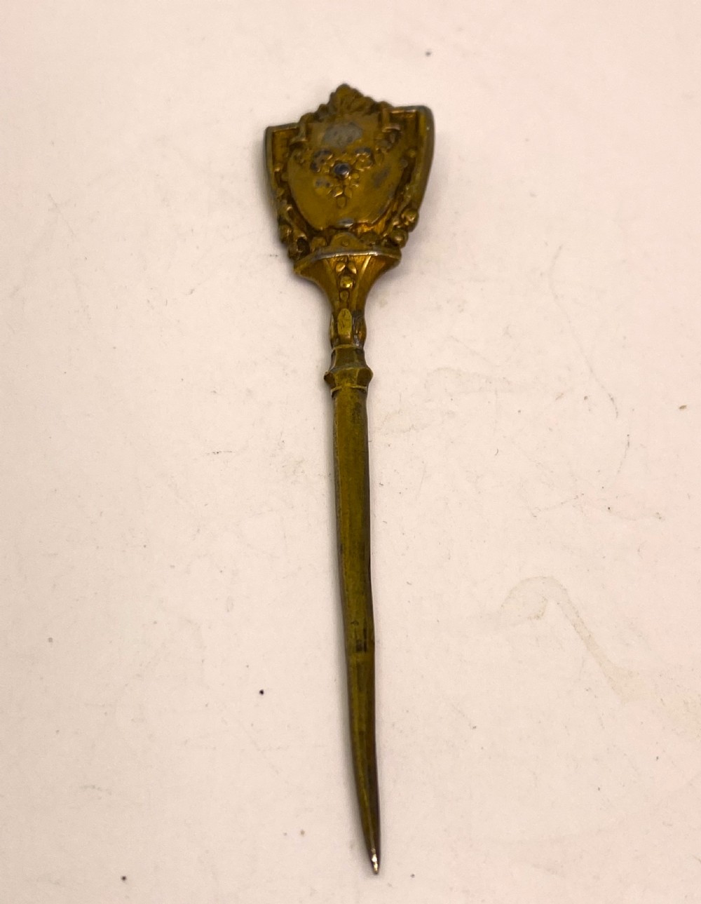 A tri-fold brown leather sewing etui open to display a cream silk interior holding gilt brass scissors, a thimble, and needlework tools. View VII