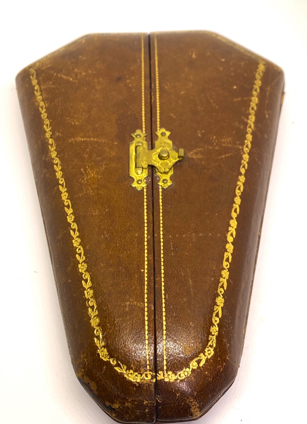 A tri-fold brown leather sewing etui open to display a cream silk interior holding gilt brass scissors, a thimble, and needlework tools. View VIII