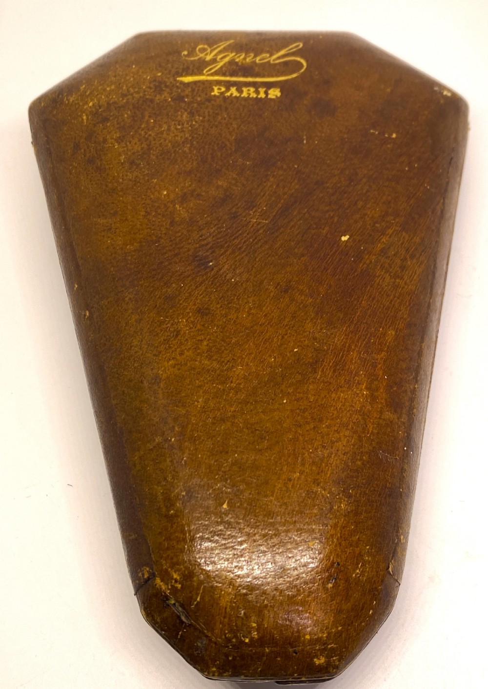 A tri-fold brown leather sewing etui open to display a cream silk interior holding gilt brass scissors, a thimble, and needlework tools. View IX
