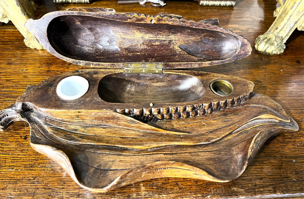 A dark hand-carved wooden double inkwell featuring two birds perched on a ear of corn with an integrated pen tray base. View III