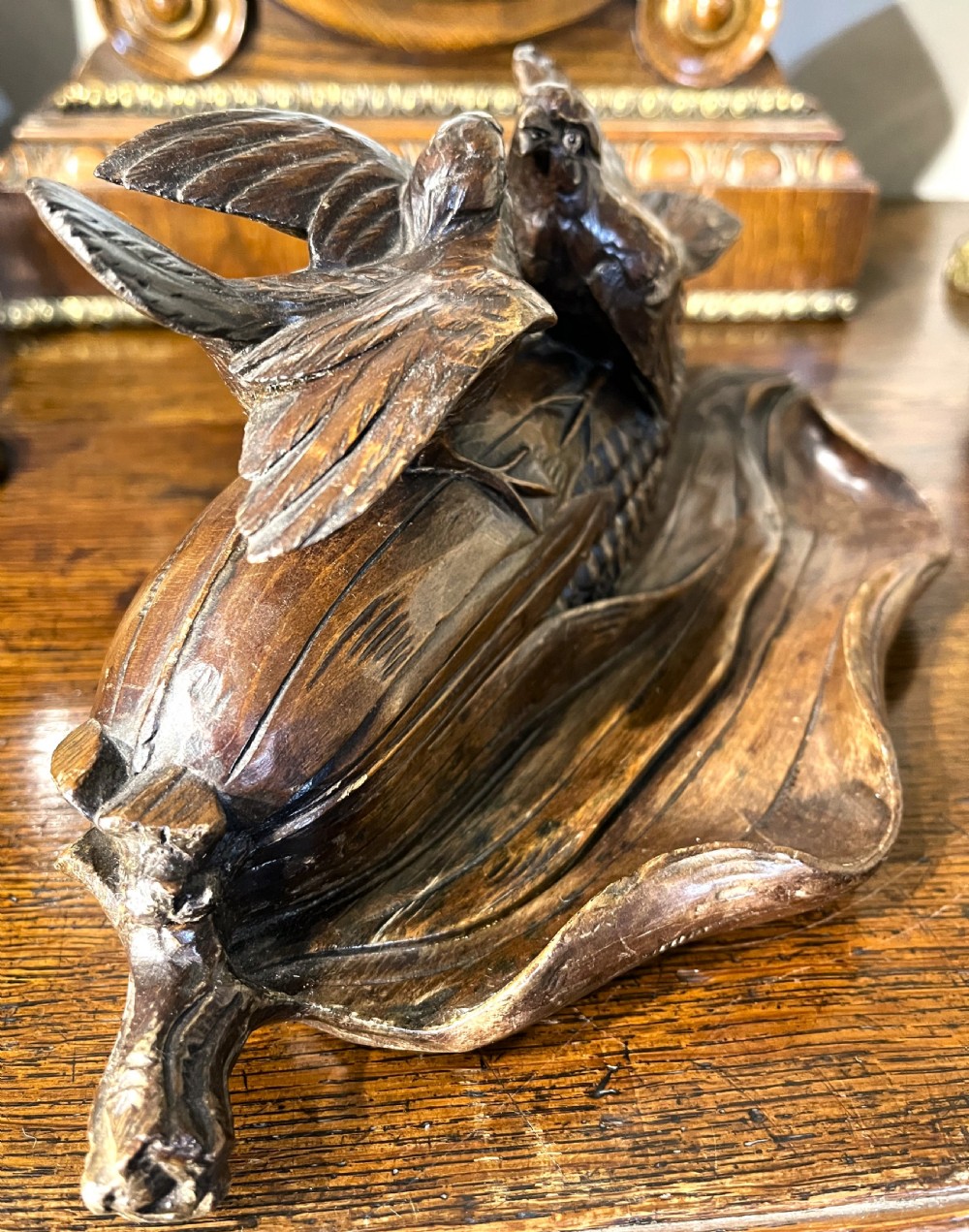A dark hand-carved wooden double inkwell featuring two birds perched on a ear of corn with an integrated pen tray base. View V