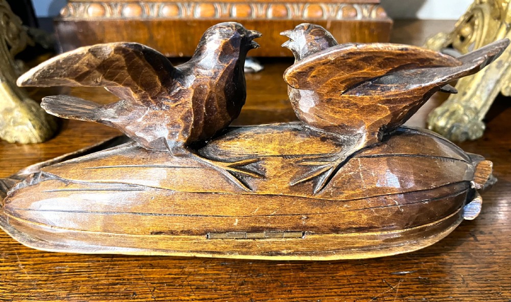 A dark hand-carved wooden double inkwell featuring two birds perched on a ear of corn with an integrated pen tray base. View VII