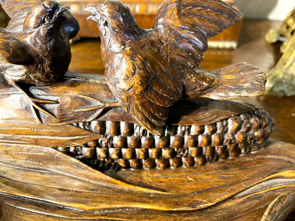 A dark hand-carved wooden double inkwell featuring two birds perched on a ear of corn with an integrated pen tray base. View VIII