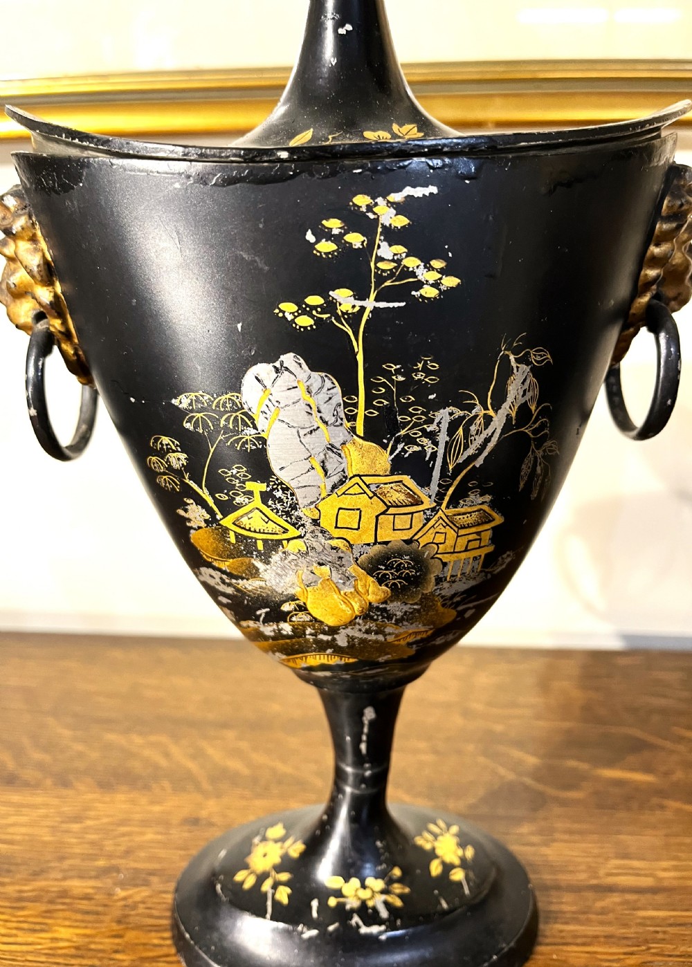 A pair of black painted metal toleware chestnut urns decorated with gold chinoiserie landscape scenes, pointed lids, and lion mask side handles. View III