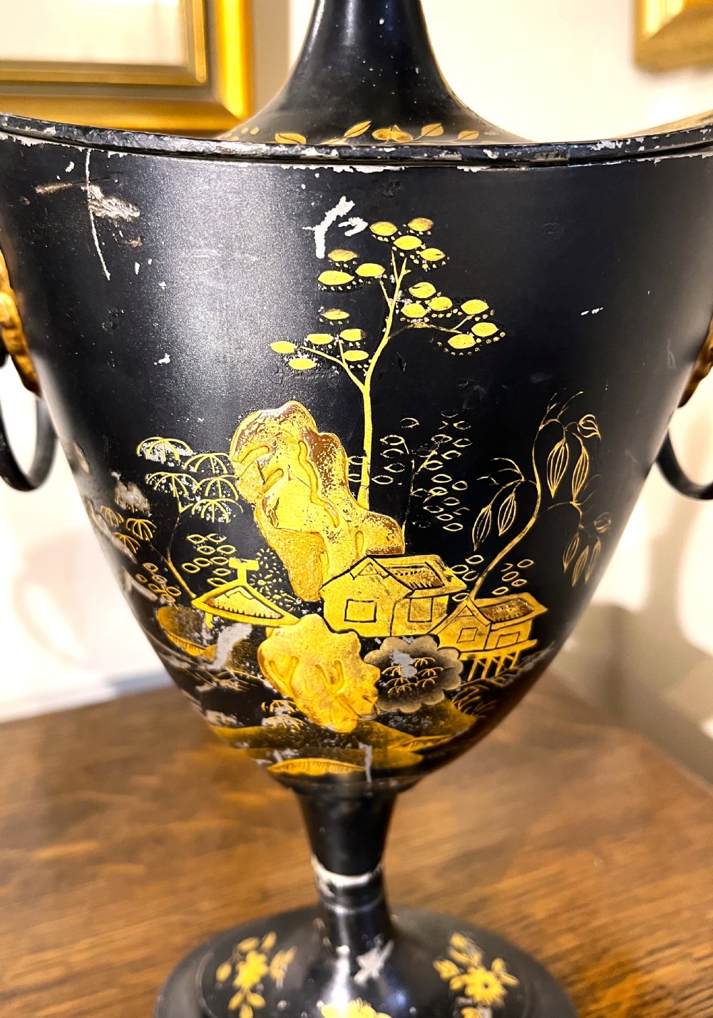 A pair of black painted metal toleware chestnut urns decorated with gold chinoiserie landscape scenes, pointed lids, and lion mask side handles. View IV