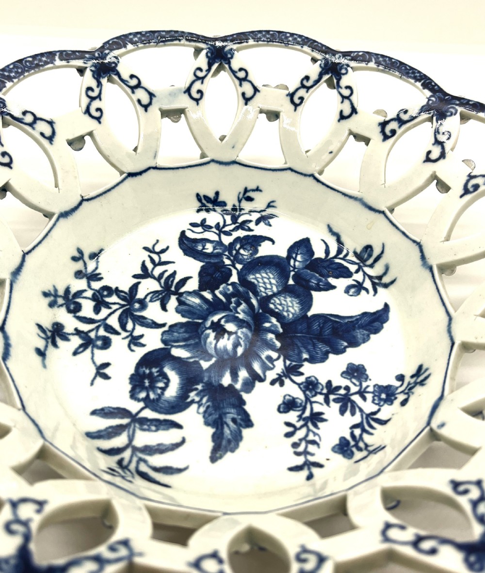 An 18th-century First Period Worcester circular soft-paste porcelain basket featuring a reticulated lattice rim and blue and white transfer-printed pinecone pattern. View II