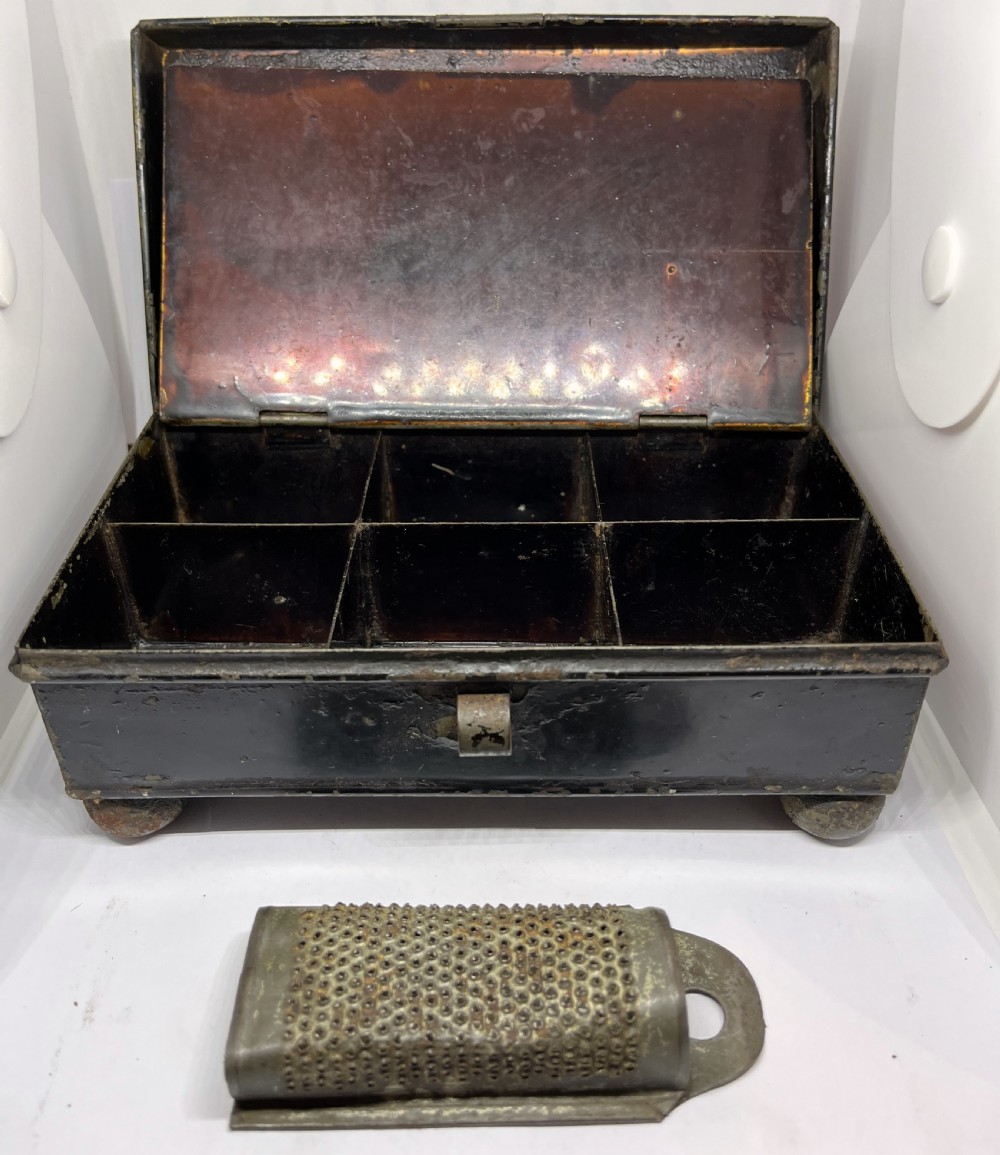 An open black lacquered toleware spice box displaying labelled inner compartments and a nutmeg grater fitted inside the lid. View III