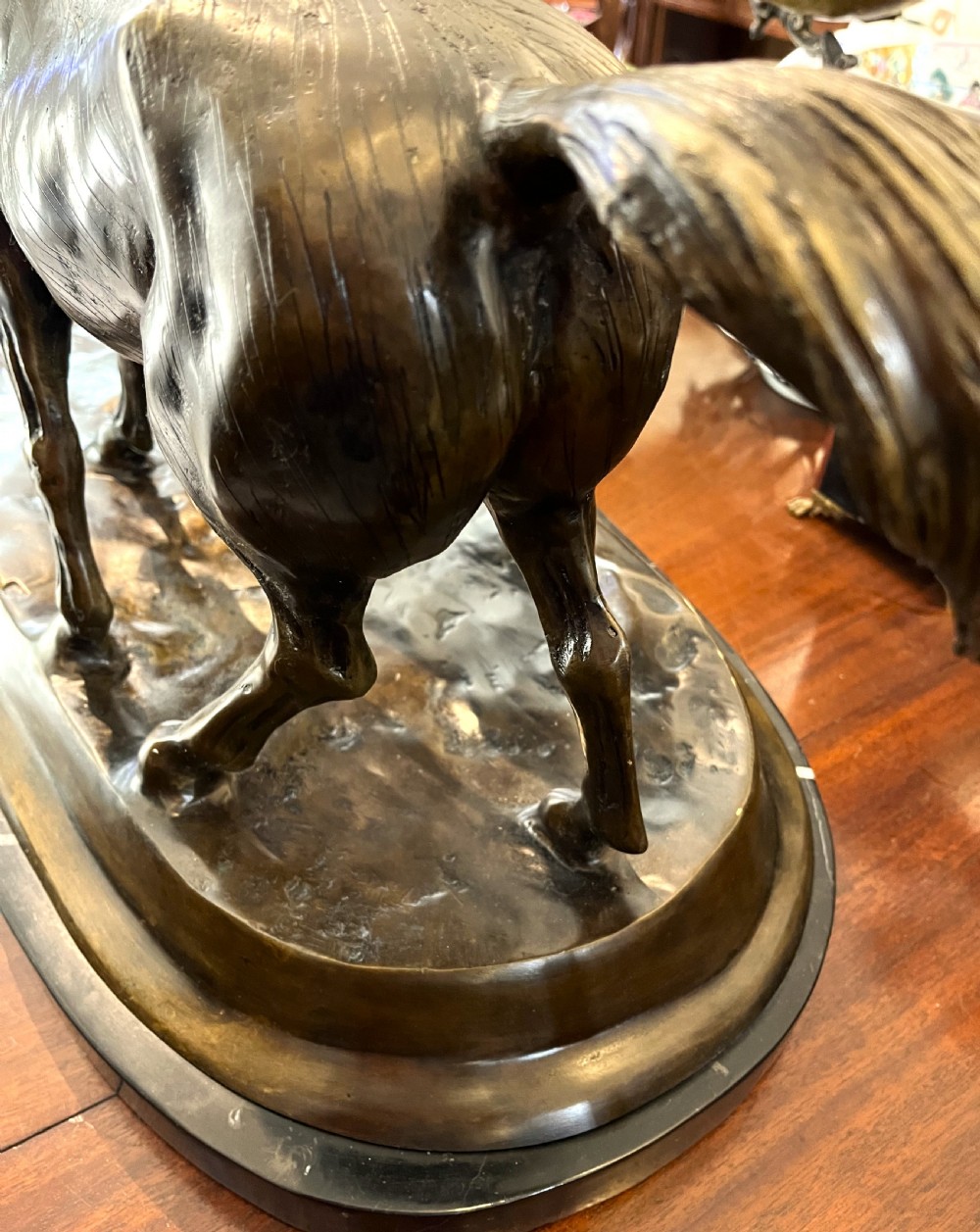 A bronze sculpture depicting two horses standing together on a naturalistic ground base mounted on an oval dark marble plinth. View XI