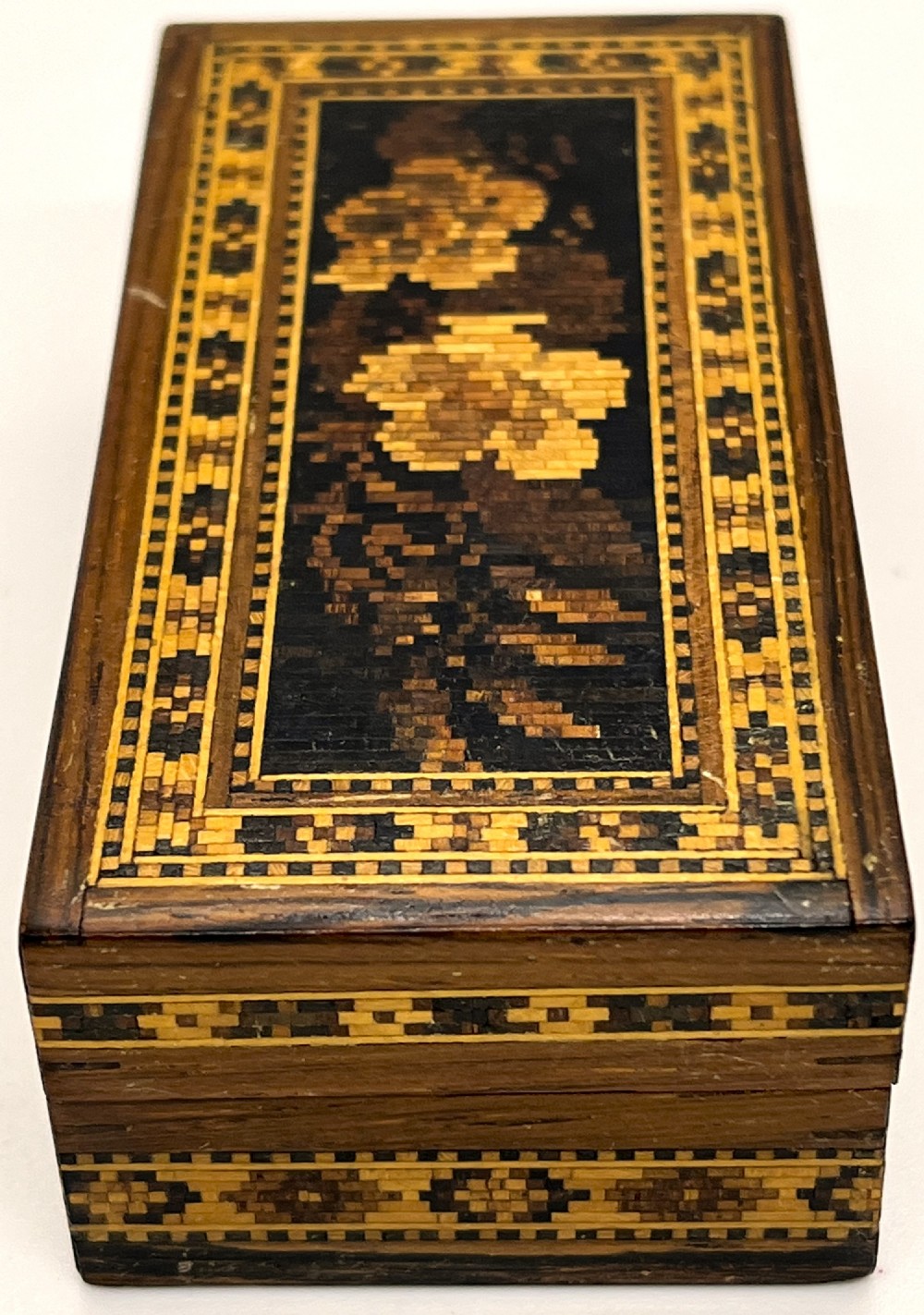 A rectangular dark wood box featuring an intricate tessellated mosaic floral design on the lid framed by geometric inlaid borders. View III