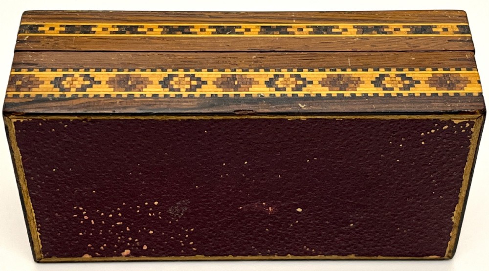 A rectangular dark wood box featuring an intricate tessellated mosaic floral design on the lid framed by geometric inlaid borders. View IV