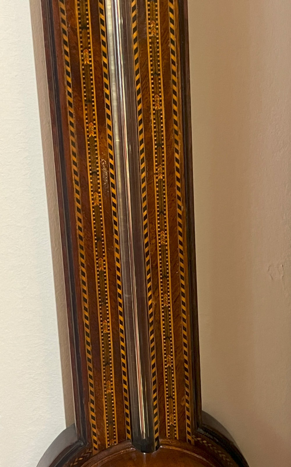 An antique Georgian mahogany stick barometer featuring geometric parquetry inlay, a broken pediment top, and an engraved silvered register plate. View II