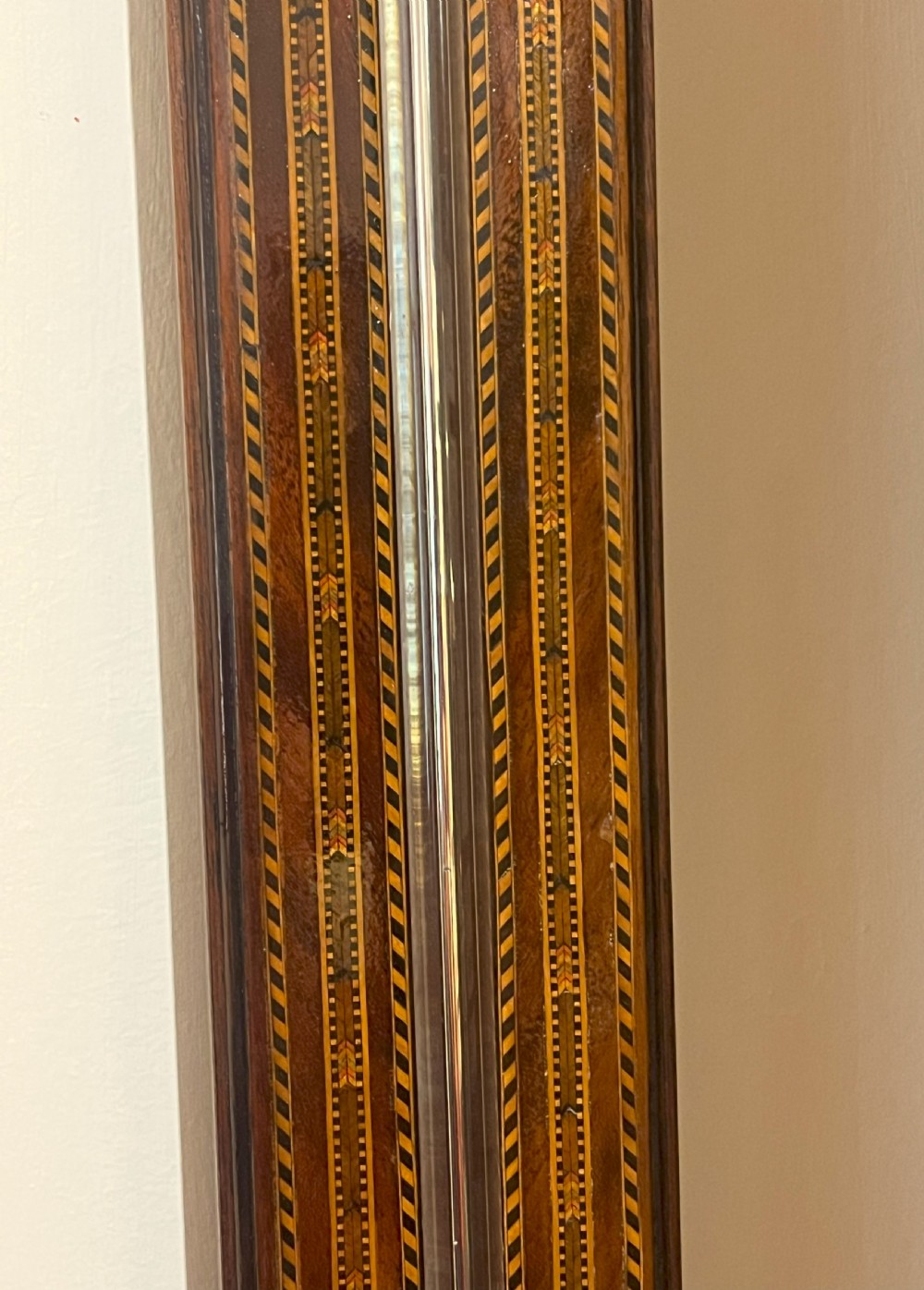 An antique Georgian mahogany stick barometer featuring geometric parquetry inlay, a broken pediment top, and an engraved silvered register plate. View IV