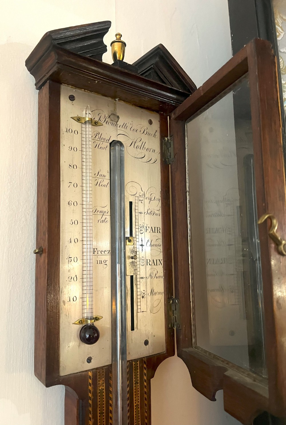 An antique Georgian mahogany stick barometer featuring geometric parquetry inlay, a broken pediment top, and an engraved silvered register plate. View XI