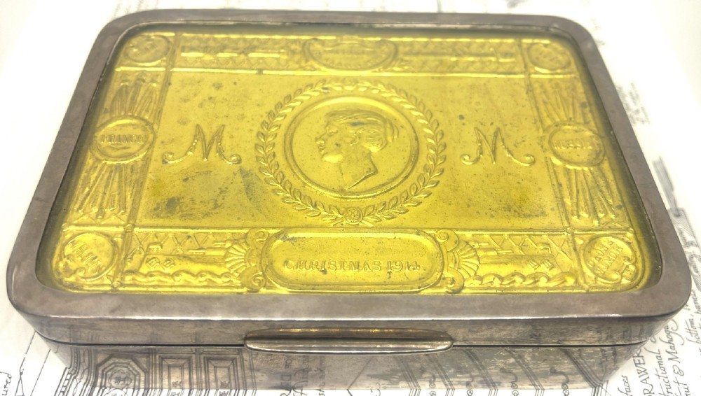 An embossed brass 1914 Princess Mary gift tin mounted inside a silver outer frame.