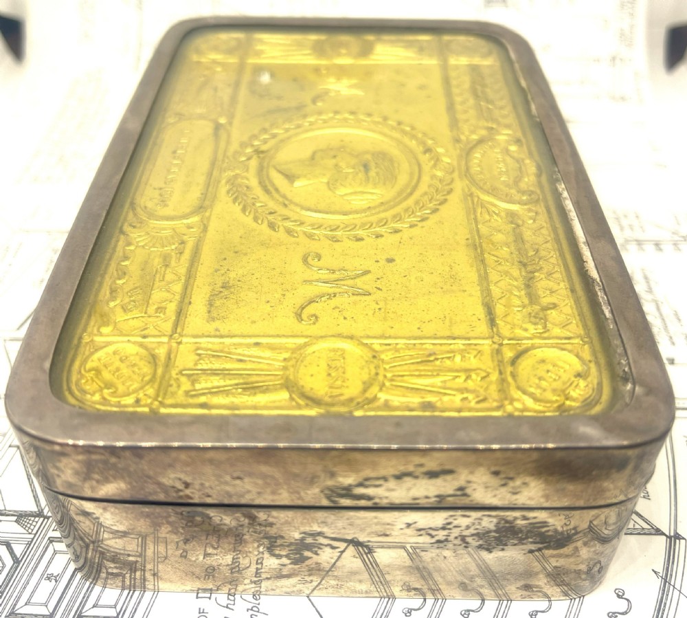 An embossed brass 1914 Princess Mary gift tin mounted inside a silver outer frame. View III