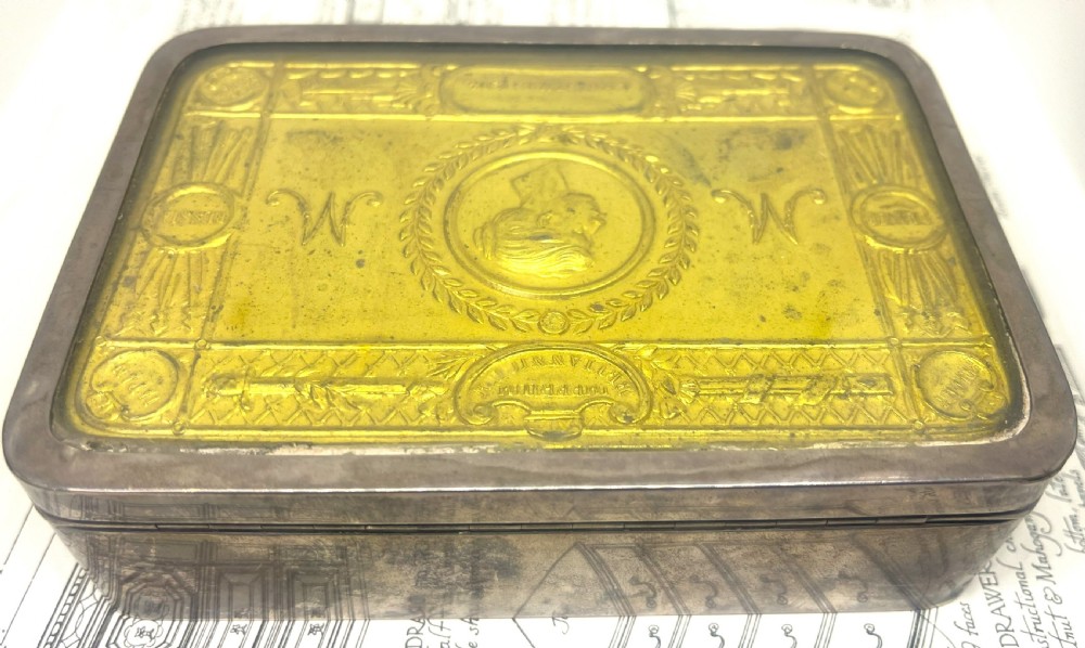 An embossed brass 1914 Princess Mary gift tin mounted inside a silver outer frame. View IV