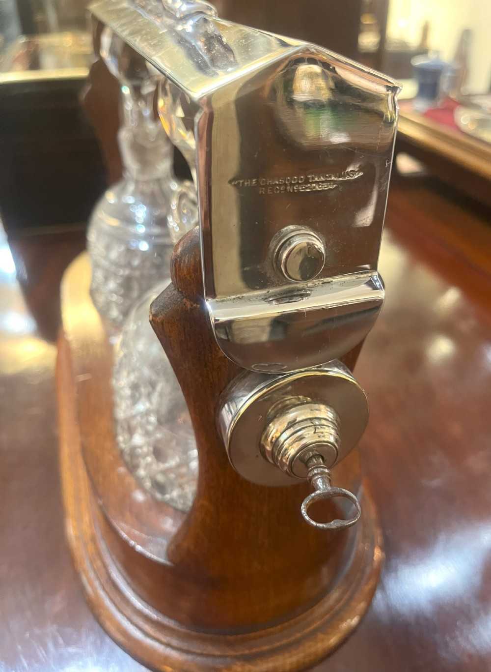 An Edwardian wooden tantalus housing two cut crystal jugs with stoppers under a silver-plated locking top bar. View II