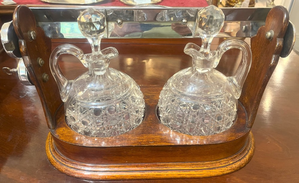 An Edwardian wooden tantalus housing two cut crystal jugs with stoppers under a silver-plated locking top bar. View III