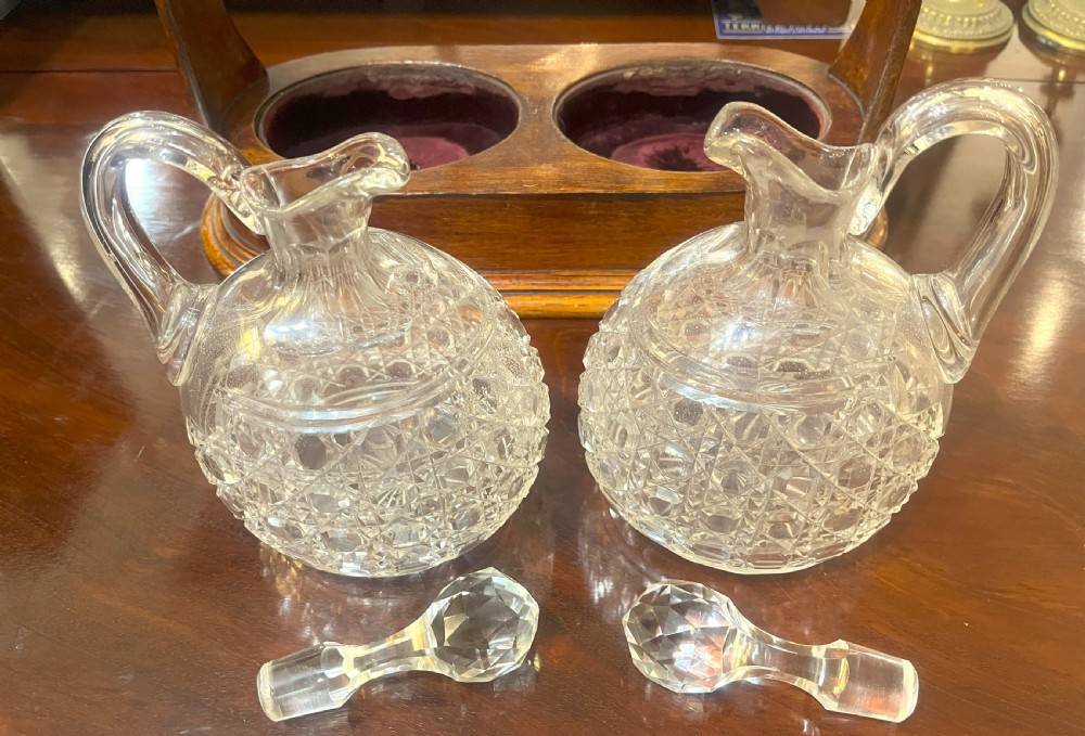 An Edwardian wooden tantalus housing two cut crystal jugs with stoppers under a silver-plated locking top bar. View V