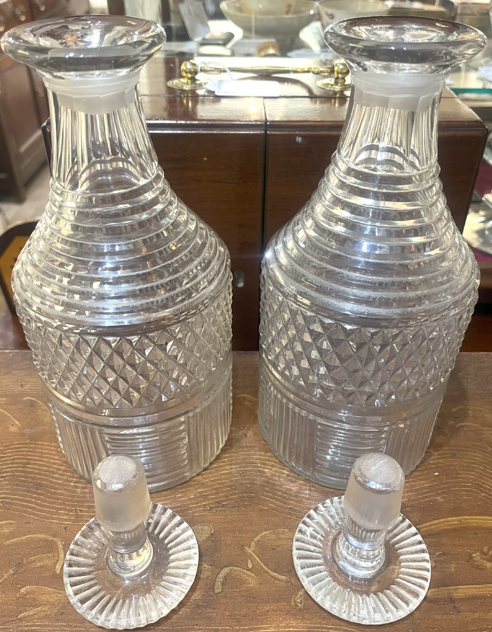 A pair of Georgian clear cut crystal decanters featuring diamond cut bands, ringed necks, and matching glass stoppers. View III