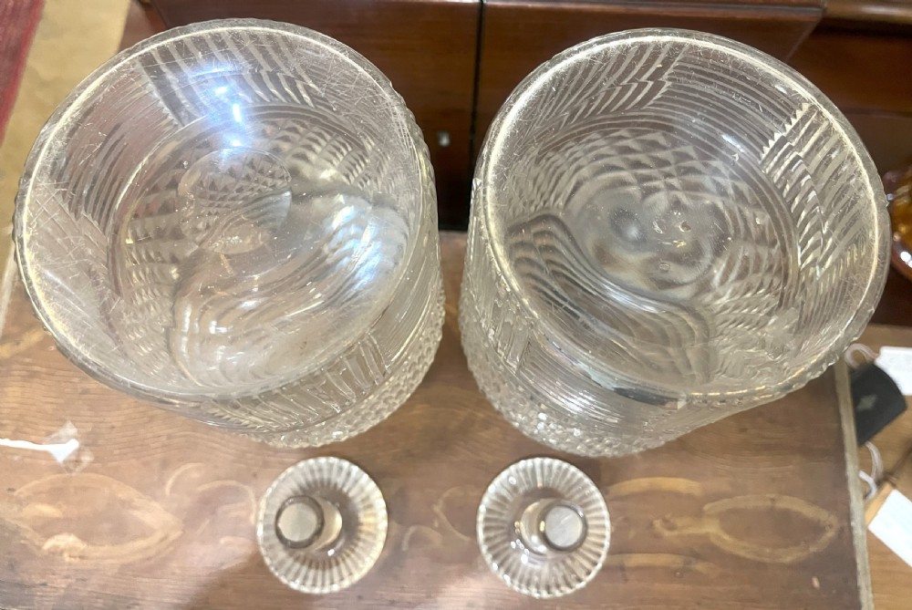 A pair of Georgian clear cut crystal decanters featuring diamond cut bands, ringed necks, and matching glass stoppers. View IV