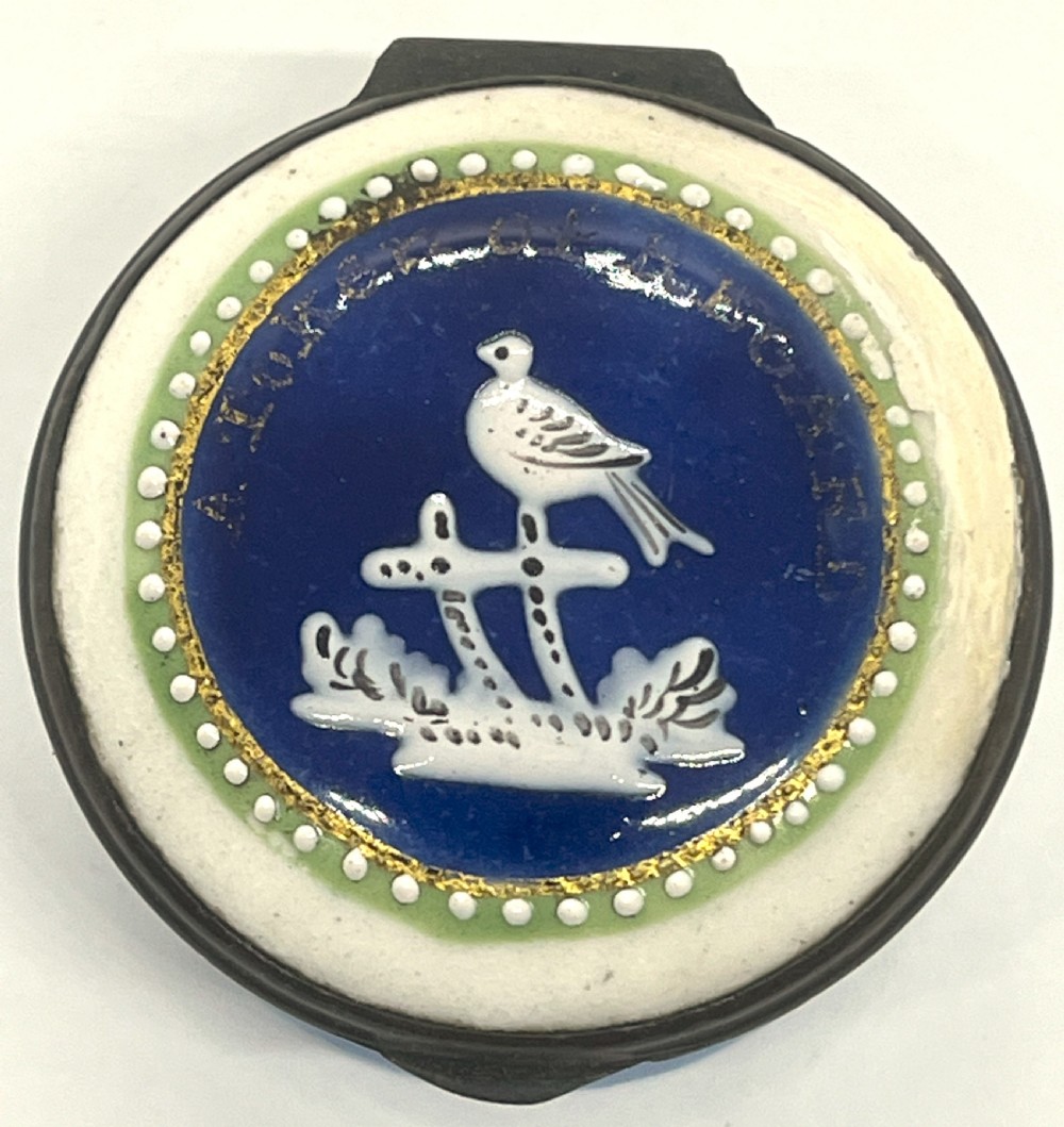 A circular Georgian South Staffordshire enamel patch box featuring a light blue base and a hinged lid adorned with a white bird motif on a navy blue ground. View II