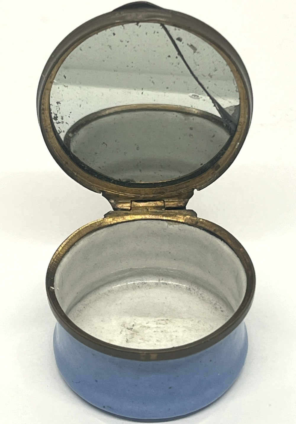 A circular Georgian South Staffordshire enamel patch box featuring a light blue base and a hinged lid adorned with a white bird motif on a navy blue ground. View V