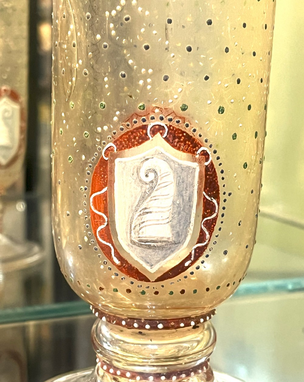 A pair of tall clear glass vases featuring hand-painted white and red enamel dot patterning and heraldic shield crests on stepped pedestal bases. View III