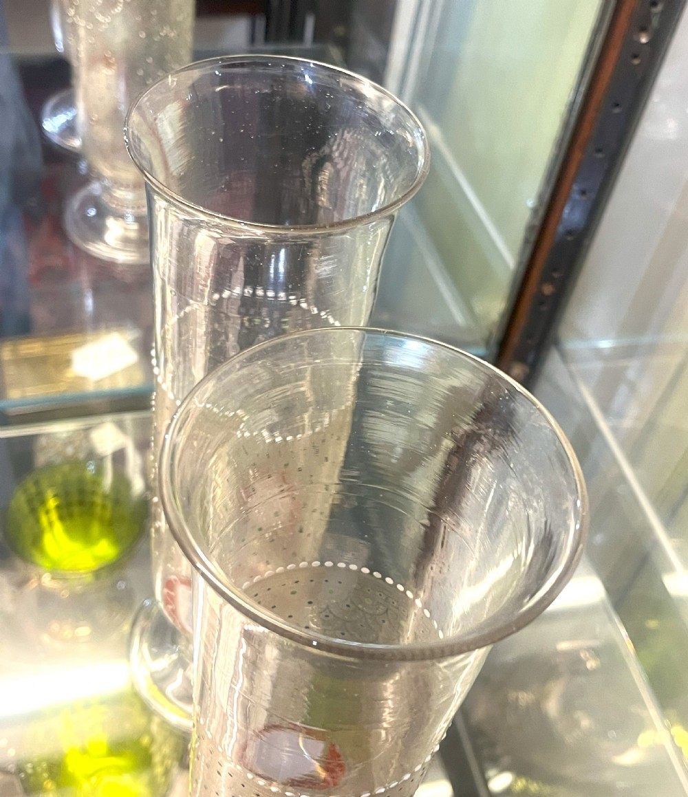A pair of tall clear glass vases featuring hand-painted white and red enamel dot patterning and heraldic shield crests on stepped pedestal bases. View VII