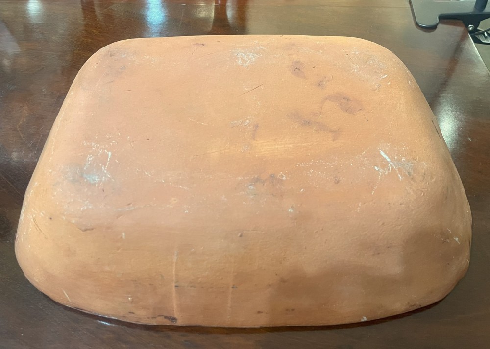 A dark brown glazed earthenware serving dish divided into two sections, featuring yellow trailed slip feather motifs along the interior. View III