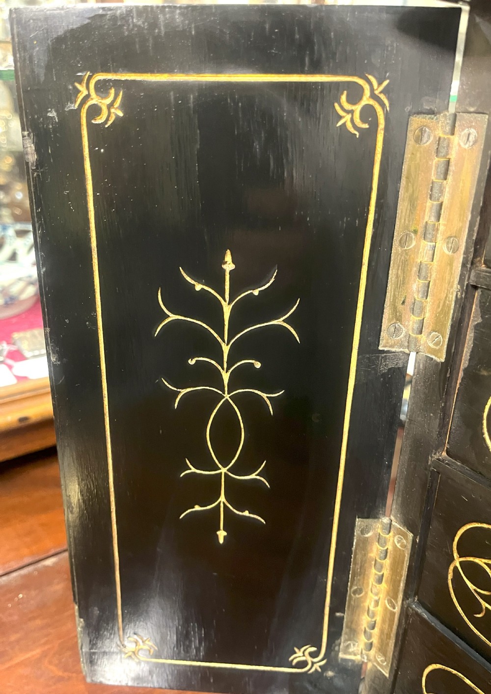 A nineteenth-century ebonised palmwood table cabinet with opened double doors revealing four small drawers with flush brass handles and gold foliate decoration. View V