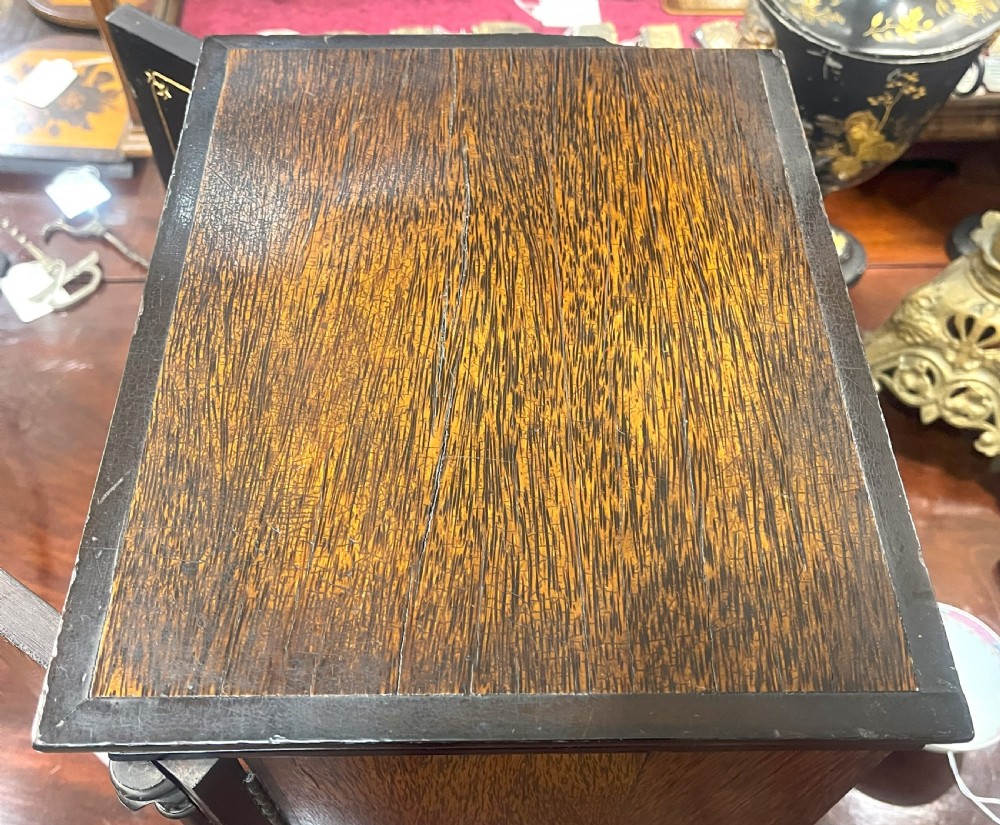 A nineteenth-century ebonised palmwood table cabinet with opened double doors revealing four small drawers with flush brass handles and gold foliate decoration. View VII
