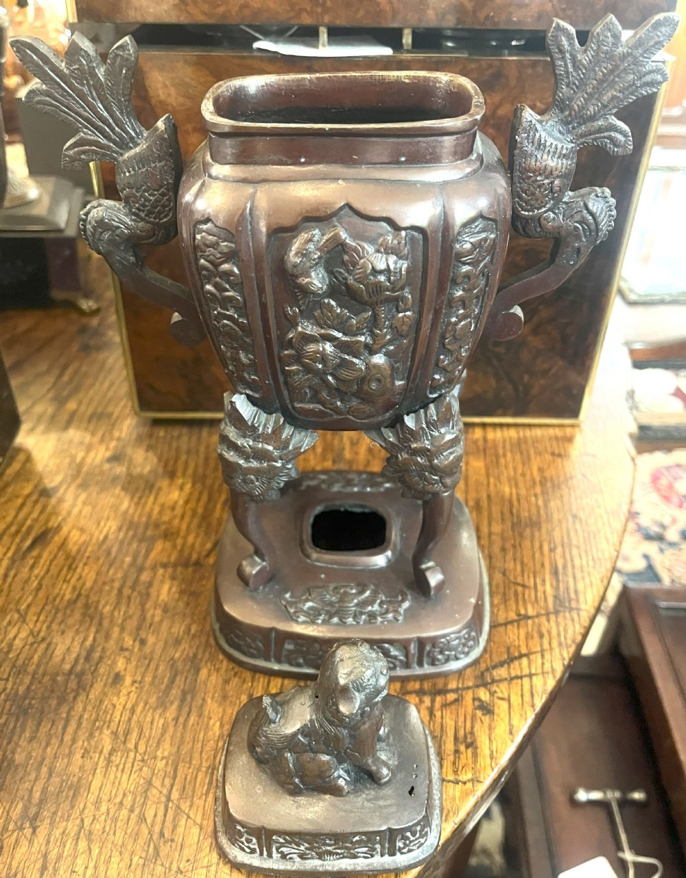 A cast dark bronze Japanese incense burner featuring a shishi guardian dog finial on the lid, floral relief panels, phoenix handles, and beast-head legs. View II