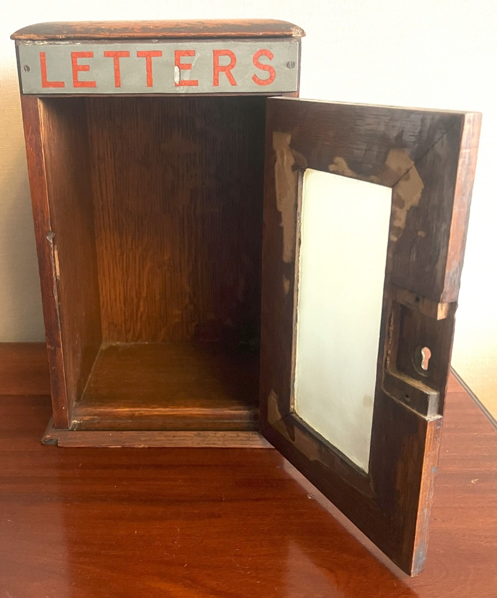 A Victorian oak postal box featuring a glazed front door with a brass keyhole, topped with a metal sign reading LETTERS in red paint. View III