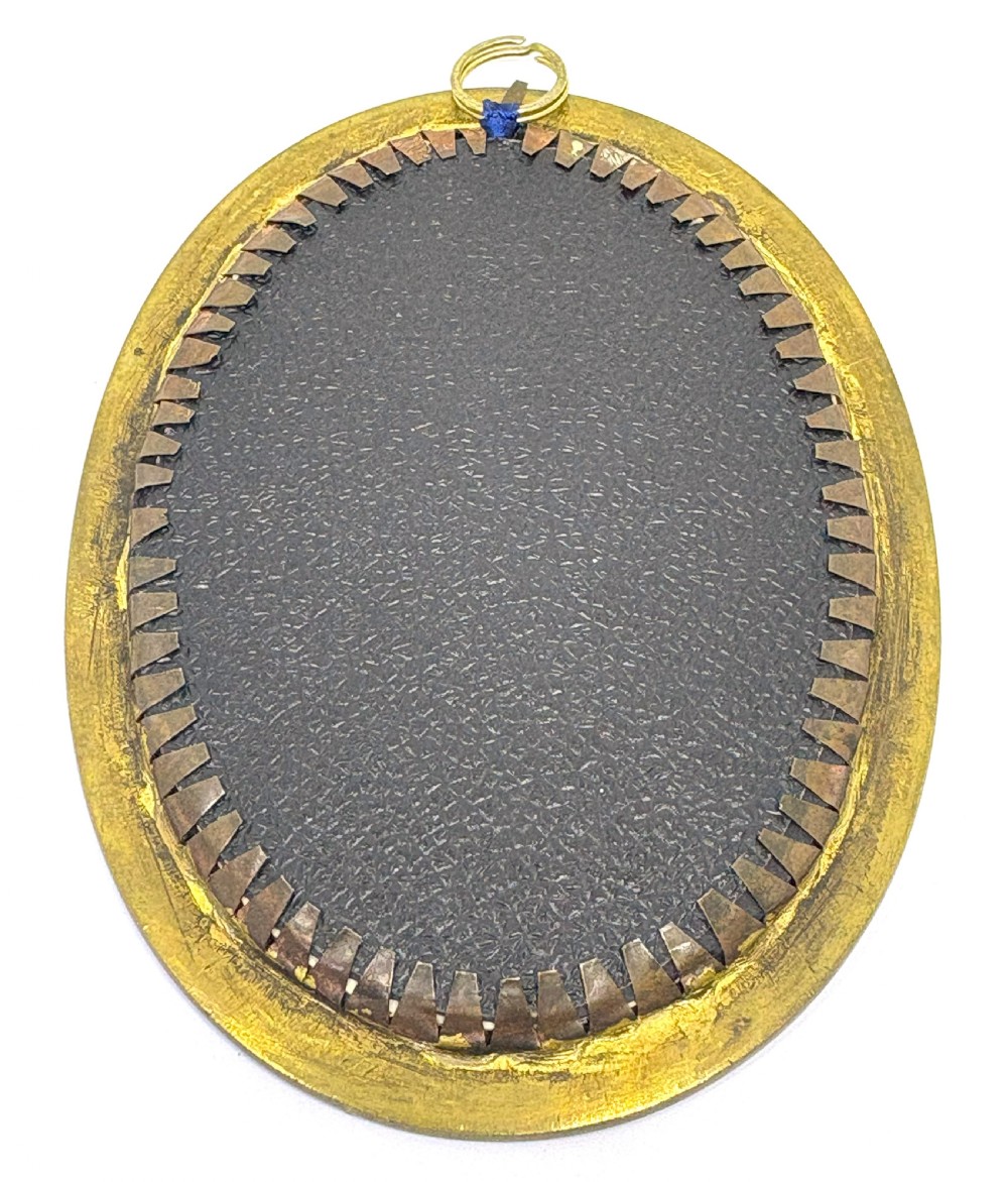 An oval 19th-century French portrait miniature depicting a woman in a blue lace gown enclosed in a beaded gilt metal frame. View II