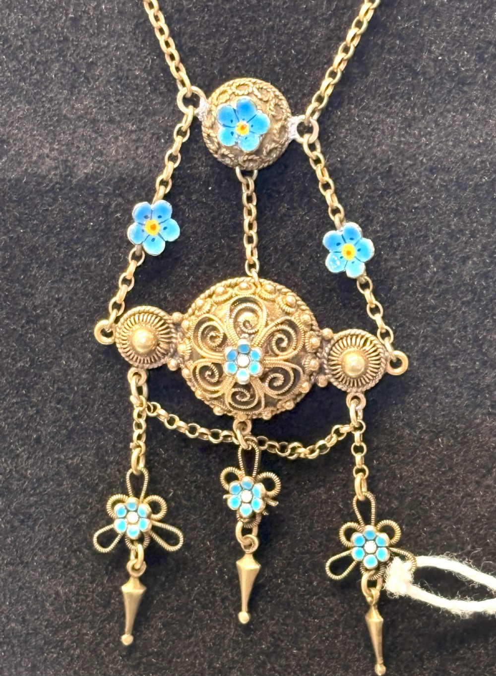 An antique gilded silver filigree pendant necklace featuring light blue enamelled flower motifs and hanging drop accents. View IV