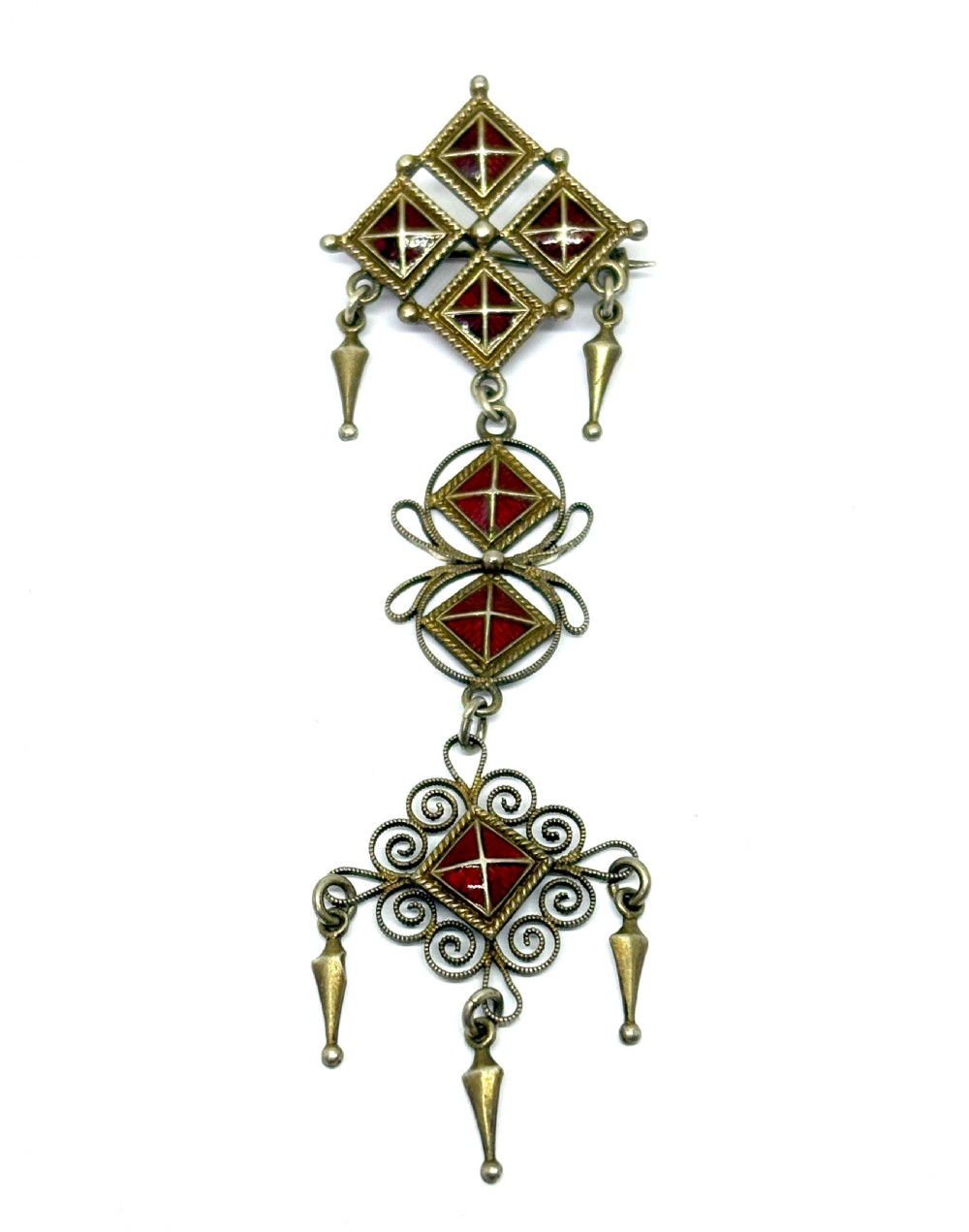 Norwegian silver gilt pendant brooch featuring diamond-shaped red guilloche enamel sections, filigree scrollwork, and suspended conical metal drops.