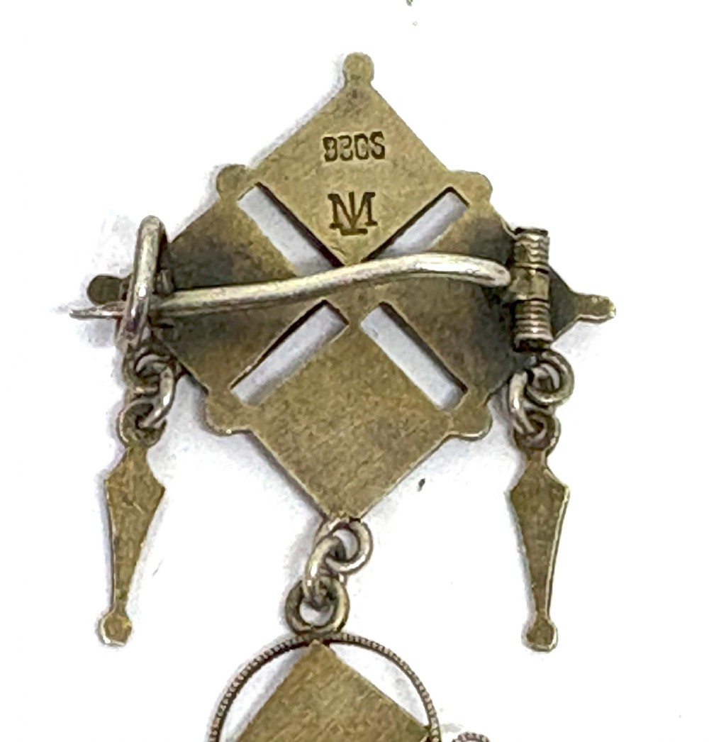 Norwegian silver gilt pendant brooch featuring diamond-shaped red guilloche enamel sections, filigree scrollwork, and suspended conical metal drops. View V