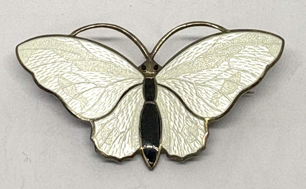 A Norwegian sterling silver and white guilloche enamel brooch crafted in the detailed form of a butterfly with a black body.