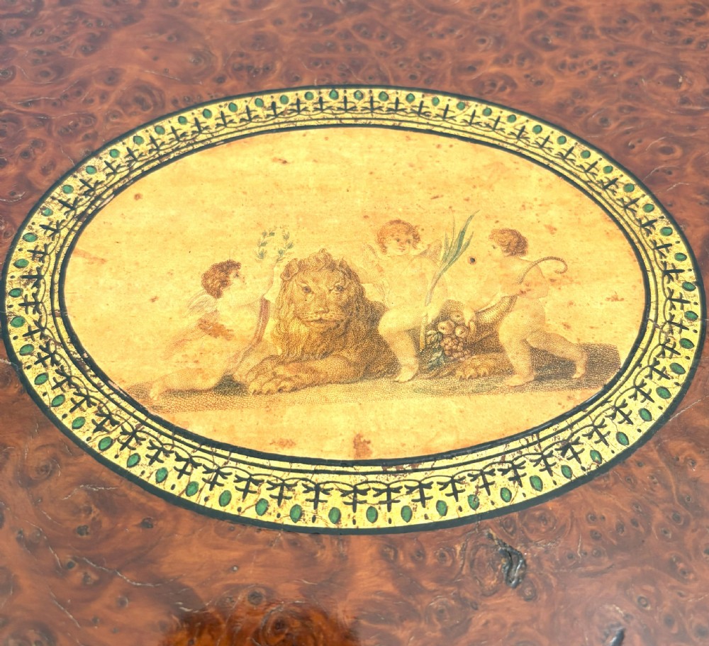 A rectangular burr yew wood box featuring a central oval medallion depicting cherubs with a lion, framed by geometric inlaid borders. View II